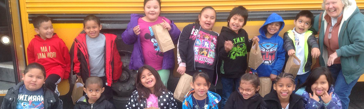 A group of excited children stands in front of a yellow school bus, ready for a fun day at school.