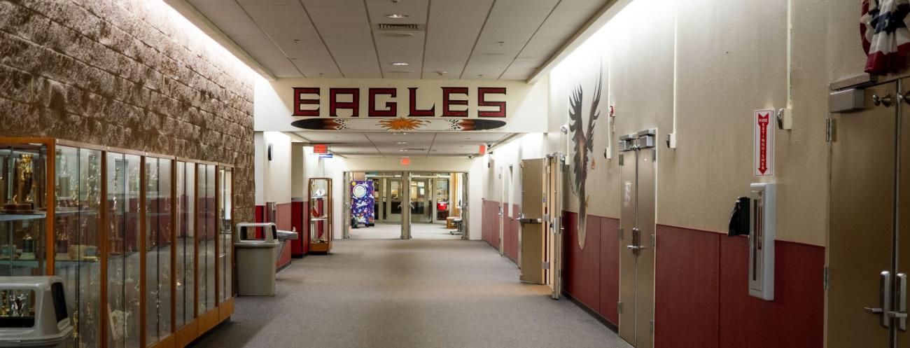 School hallway lined with numerous display items and an Eagles sign above doorway.